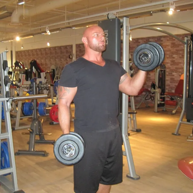 Mann løfter manualer for å trene bicep