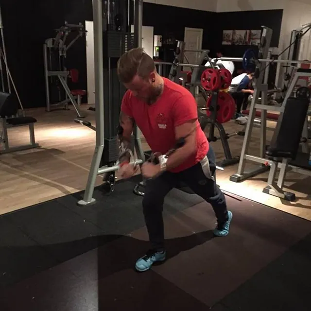 Mann står og trener bryst med kabler