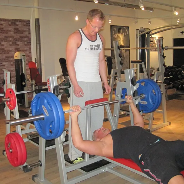 Mann med briller spotter person i benkpress