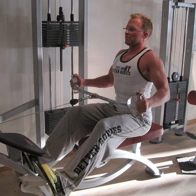 Mann med briller sitter i ro-maskin og trener
