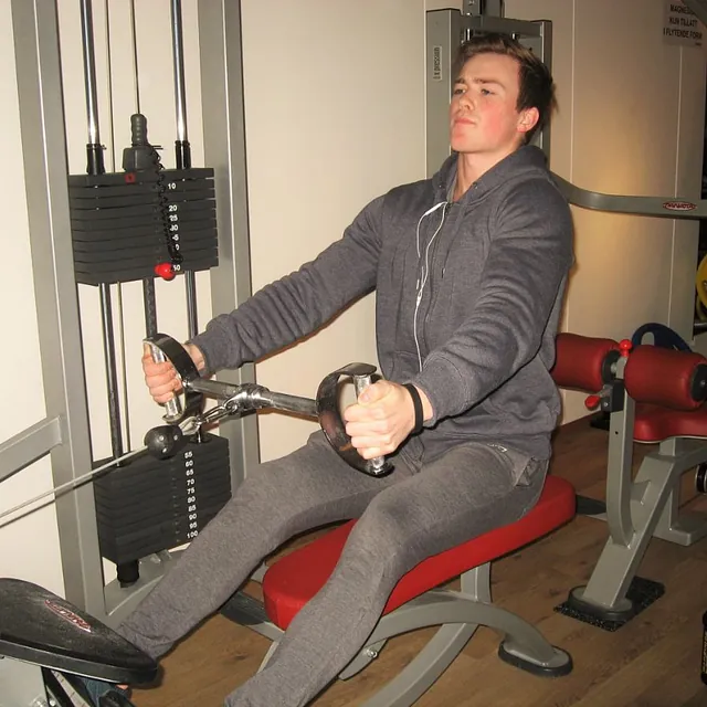 Mann i hettegenser trener i ro-maskin