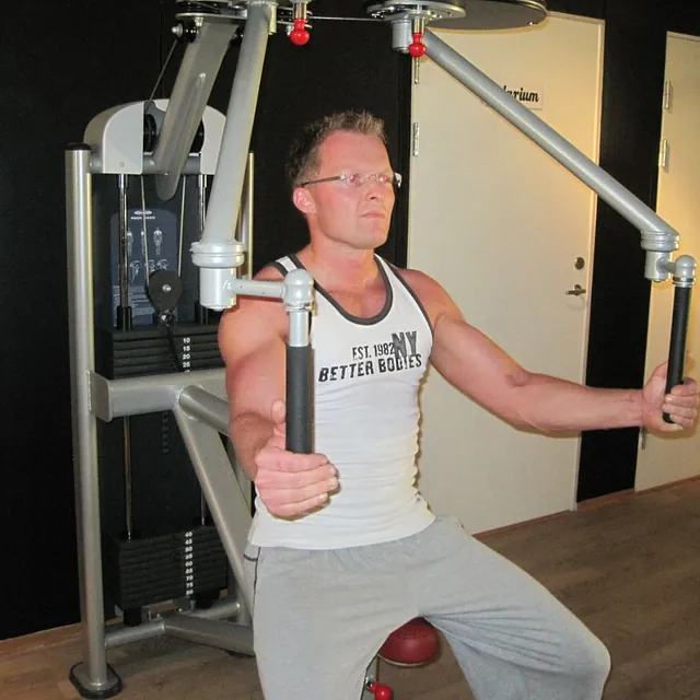 Mann med briller trener i treningsapparat