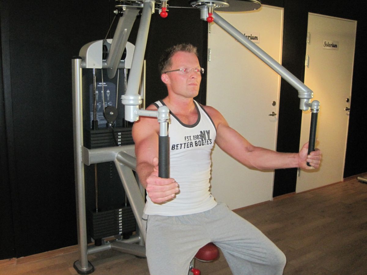 Mann med briller trener i treningsapparat