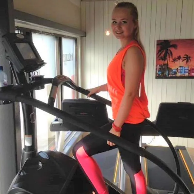 Jente med blondt hår bruker stairmaster og ser i kamera