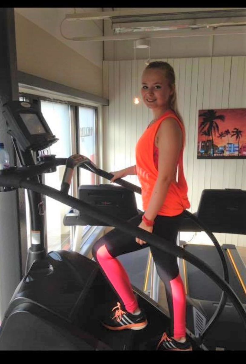 Jente med blondt hår bruker stairmaster og ser i kamera